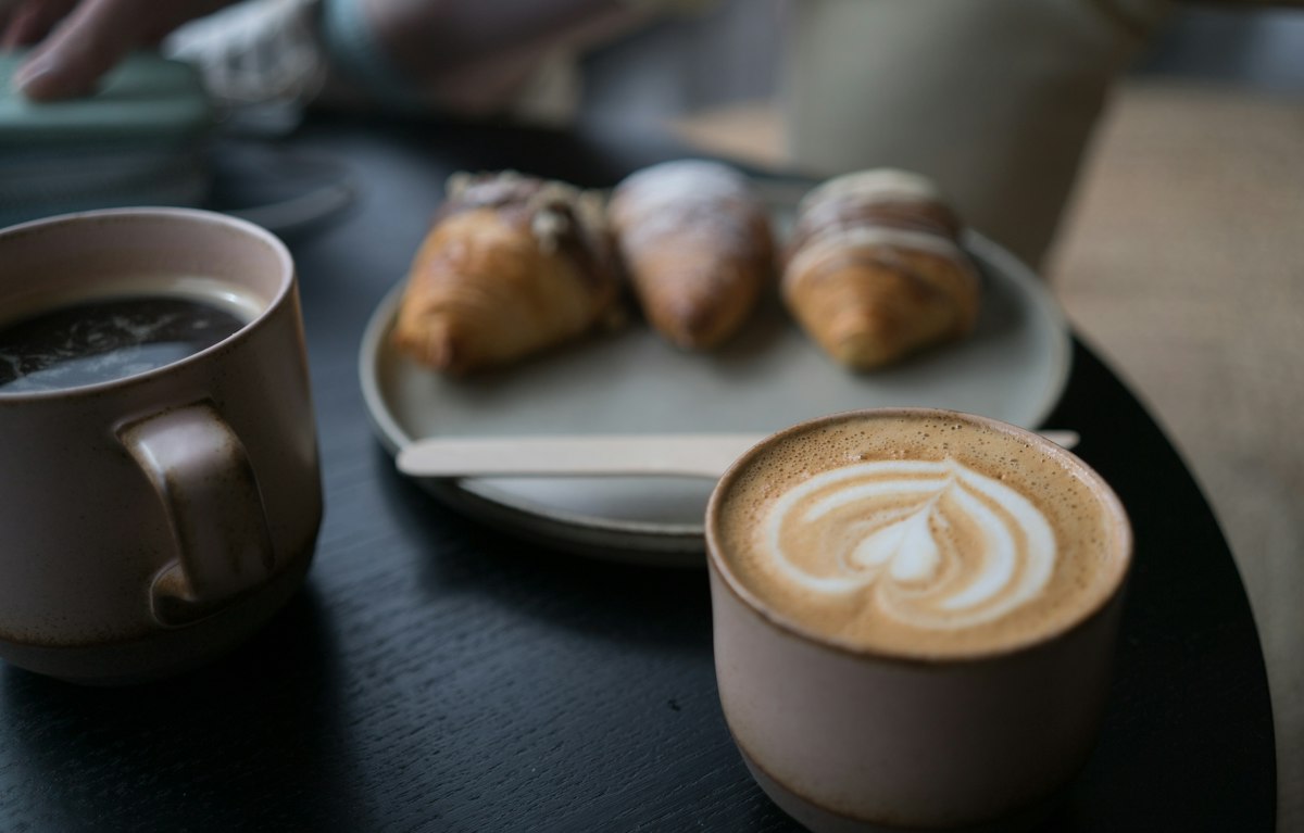 two brown and white ceramic coffee cups on black wooden table