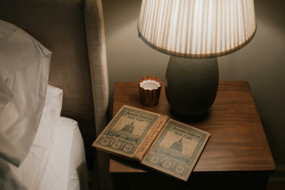 Open book on bedside table with lamp
