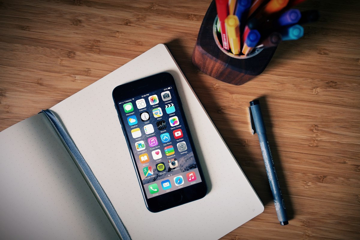Phone, notebook, pen, and pens on a desk