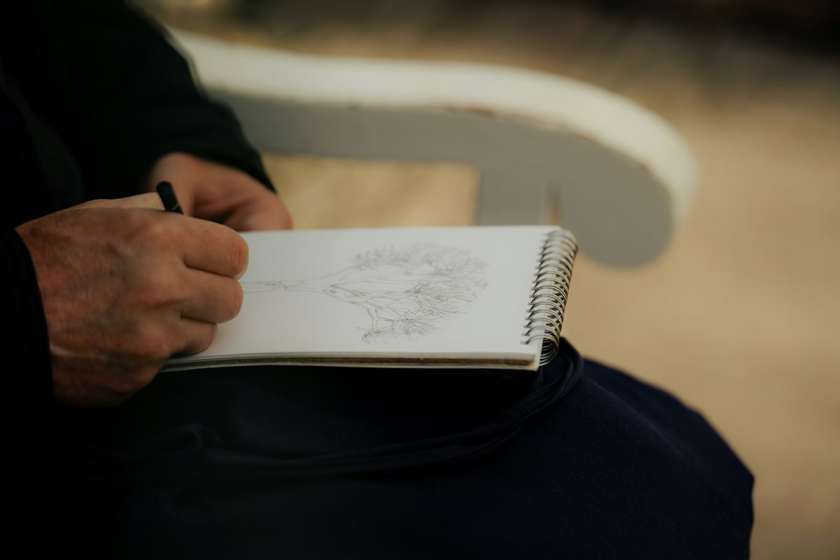 Hands drawing in a notebook with a pencil