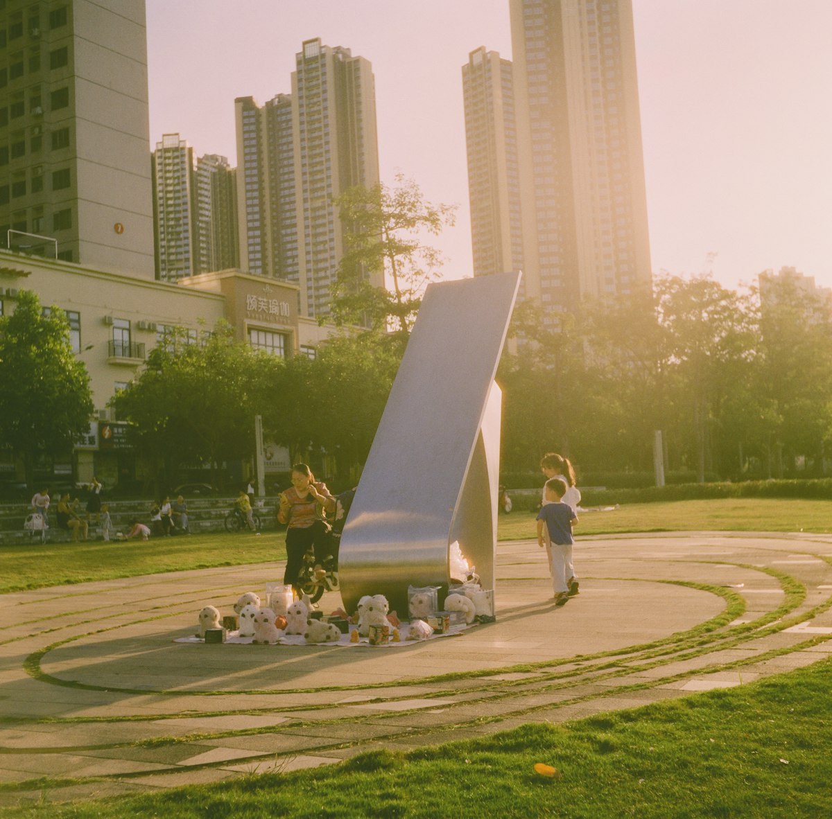 People gather around a modern sculpture in a park