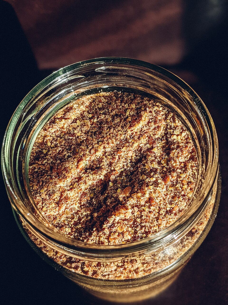 Ground flax seeds in a glass jar illuminated by window light (51173270515)