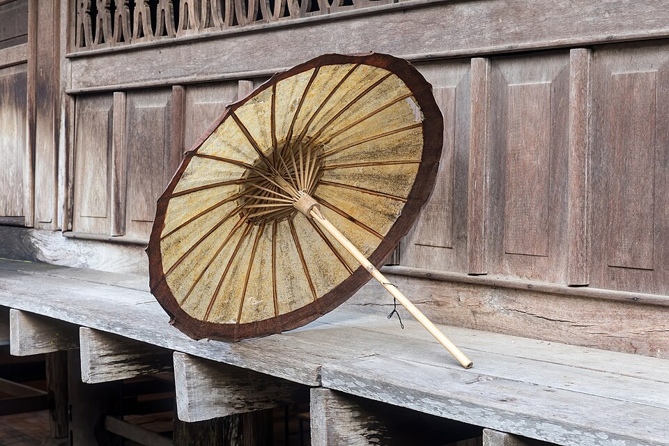 Beige and brown oil-paper umbrella on the edge of a wooden house in Luang Prabang Laos