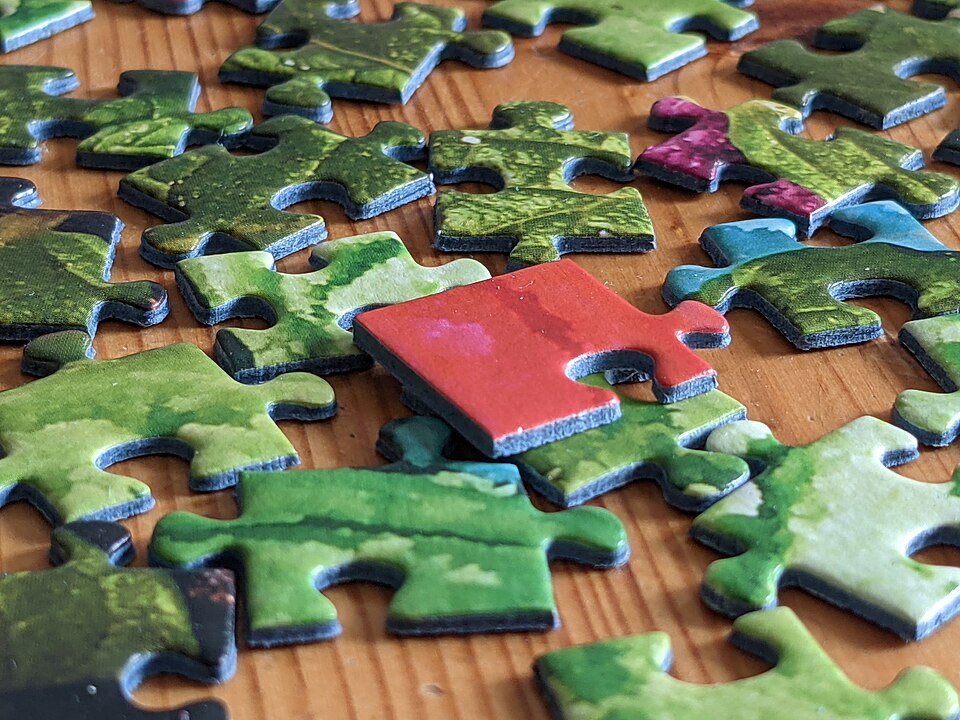 Red jigsaw puzzle piece on green pieces