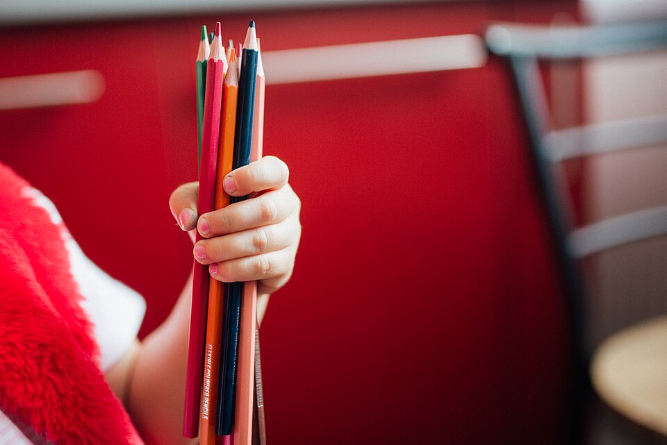 A young hand grips a bundle of vibrant colored pencils, ready for artistic expression