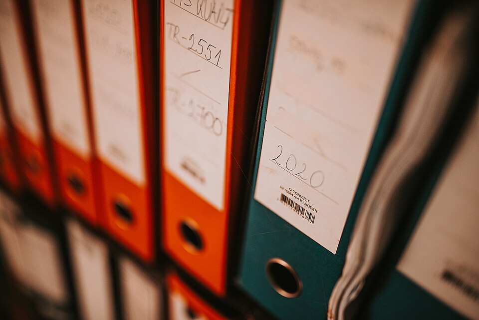Collection of colorful binders on a shelf for storing documents in an office setting