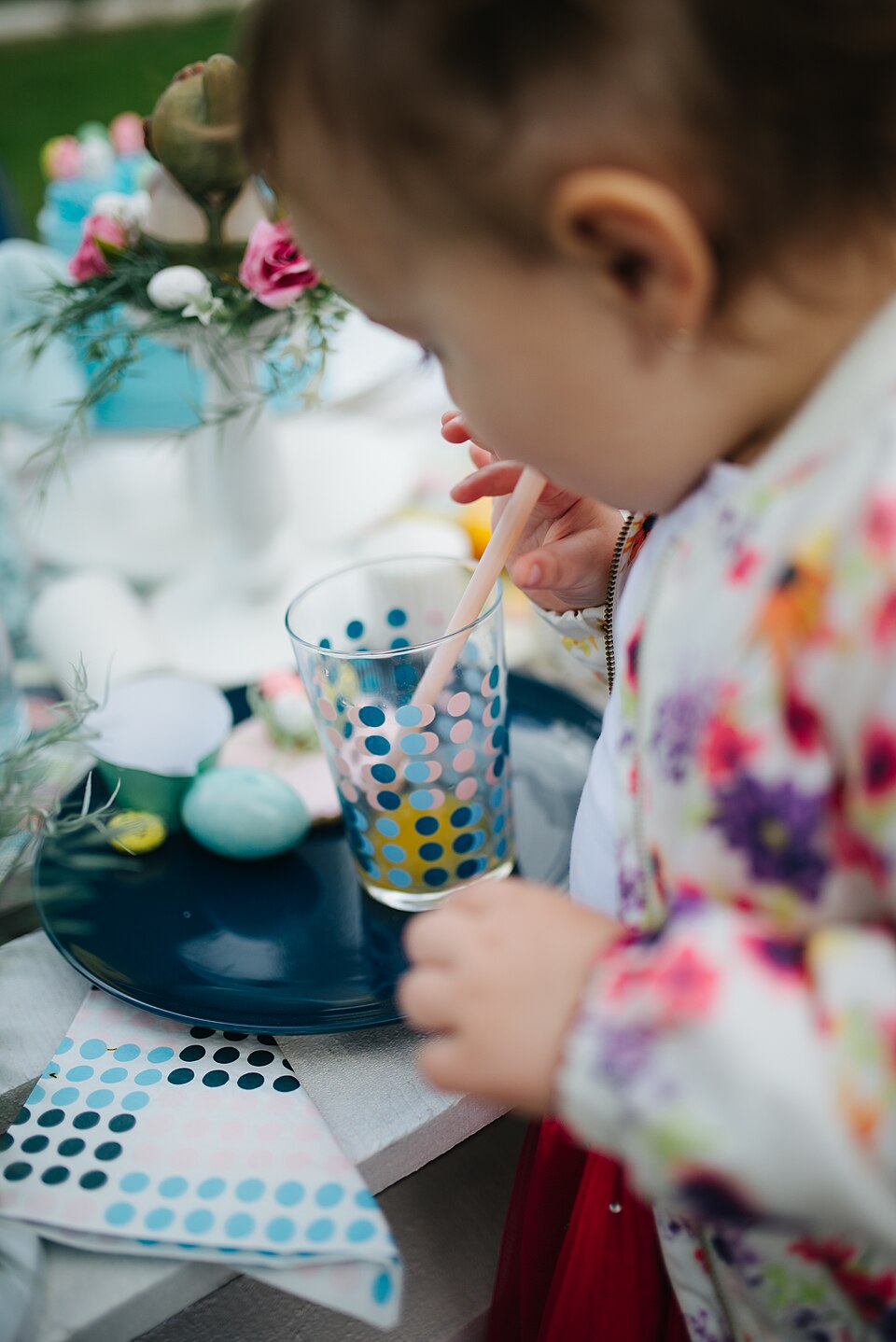 Child enjoys drink at a colorful table setting during a festive gathering