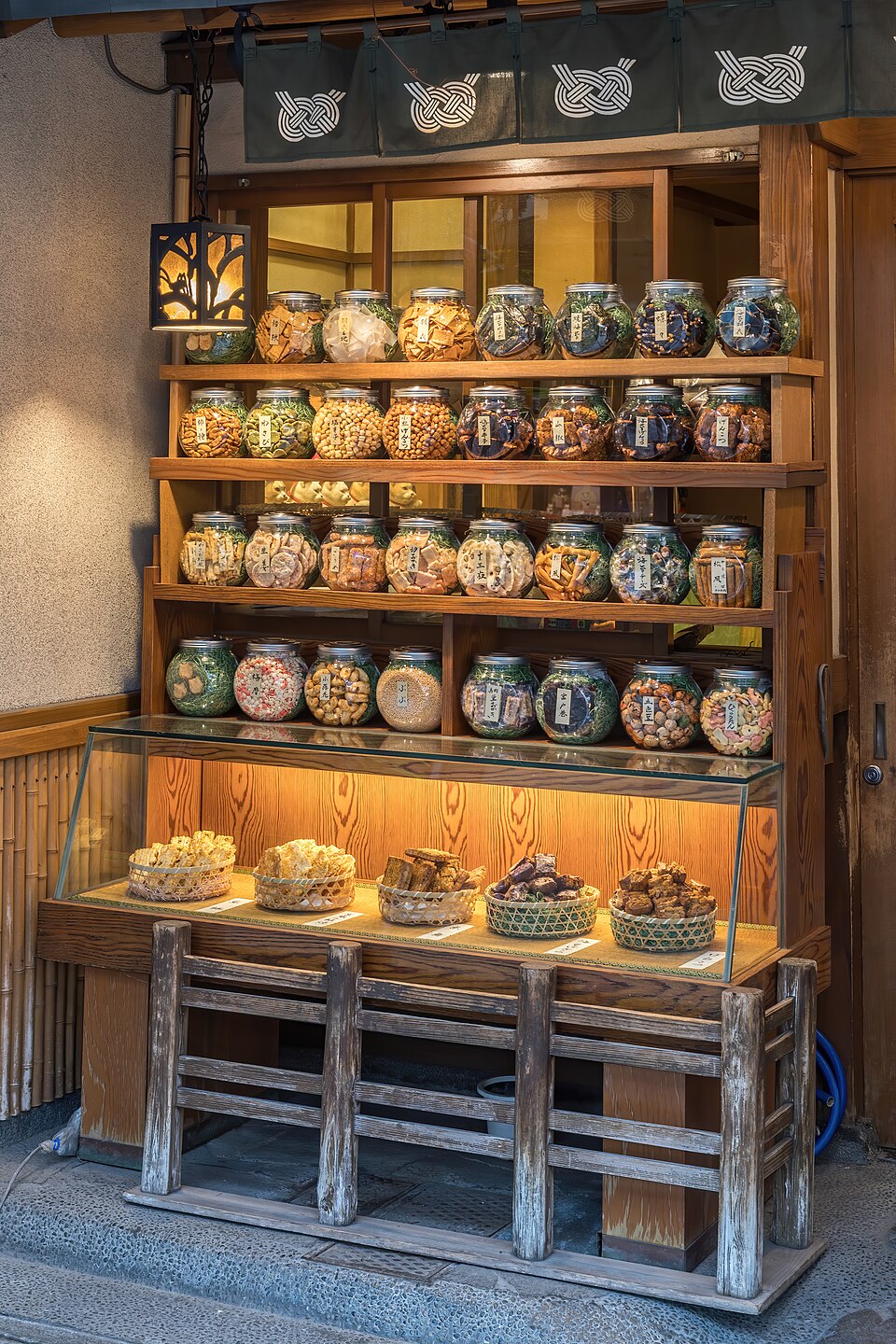 Illuminated wooden shelf with many glass jars containing cookies for sale in Tokyo